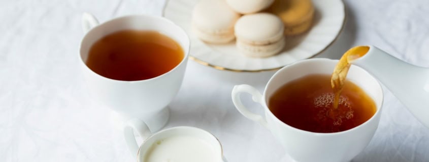 two cups of coffee beside the macaroons on plate